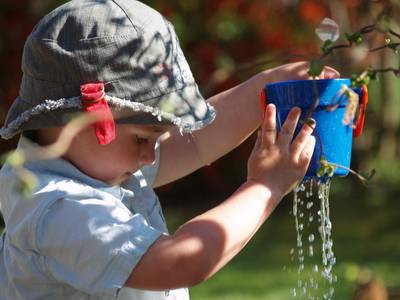 Quelle: pixabay.com / igrow, https://pixabay.com/de/photos/kind-spielen-wasser-tropfen-eimer-392971/ Kind hält Plastikeimer aus dem Wasser tropft